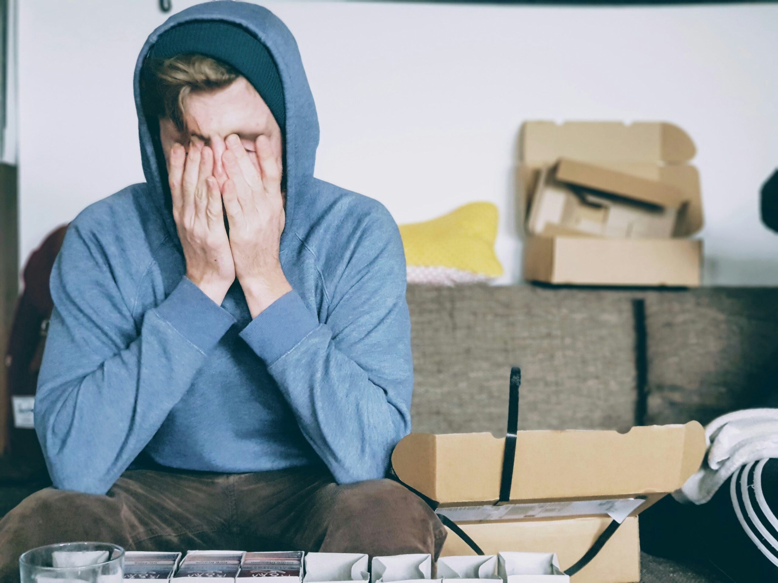 Adult sitting with head in hands, feeling stressed and overwhelmed — symbolising the challenges of ADHD and the benefit of an Adult ADHD assessment.